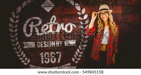 Gorgeous smiling blonde hipster posing against texture of bricks wall