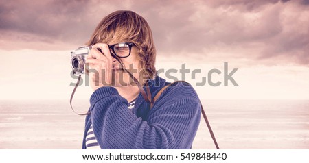 Hipster taking pictures with an old camera against cloudy landscape background