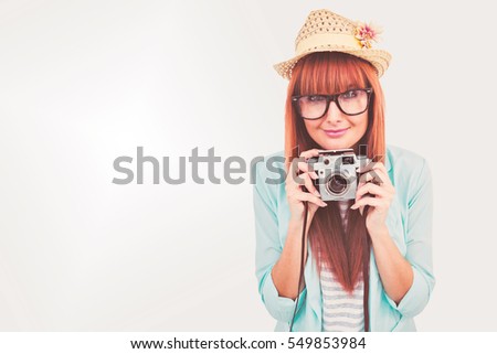 Portrait of a smiling hipster woman holding retro camera against grey background