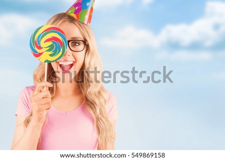 Portrait of a hipster hiding herself behind a lollipop against blue sky