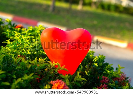 Red heart balloon isolated on green leaf in blur background select focus balloon