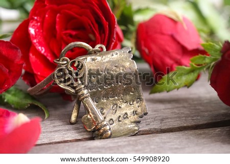 Vintage keys with red roses on the background, distressed vintage key necklace with bronze hand writing script paper. Love, key to my heart and Valentine's concept.