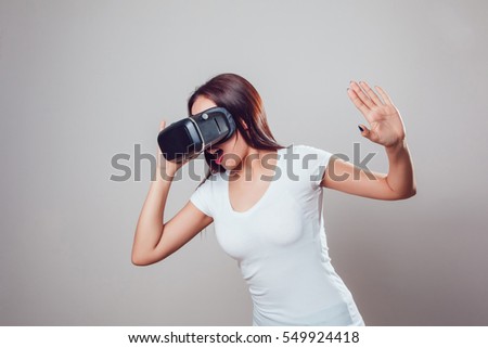 Attractive woman using virtual reality goggles on grey background. VR headset.