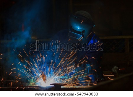 Industrial worker is welding in automotive factory