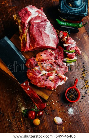 raw meat on rustic, vintage table with spices, vegetables and knife, hatchet