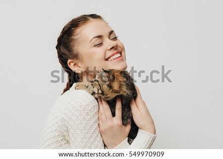 A smiling young girl with a kitten in his hands