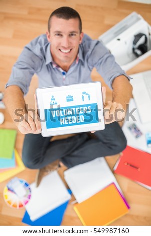 Yellow volunteers needed against businessman showing tablet computer in creative office
