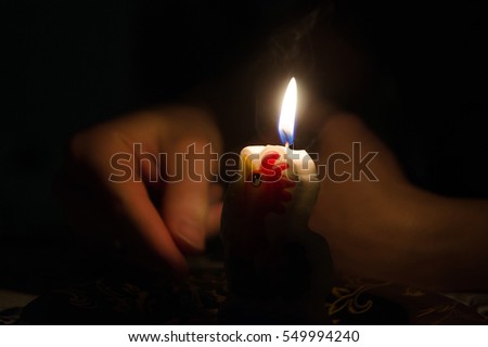 hand in the dark, lights a match and brings to the candle with a chicken picture