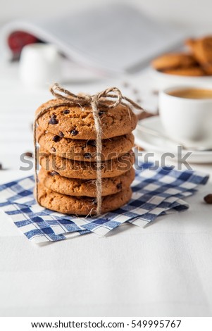 Oatmeal cookies, coffee grains and cup of hot coffee on white table