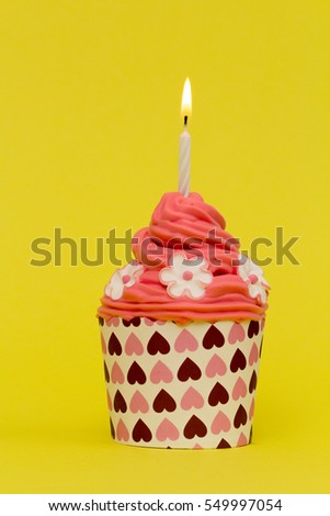 cupcake with burning candle and yellow background