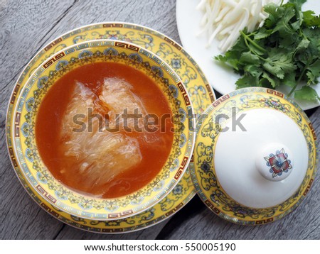 Chinese Shark's Fin Soup with brown sauce serve in Royal yellow bowl, decoration with  bean sprouts and Coriander, on grey wooden background.