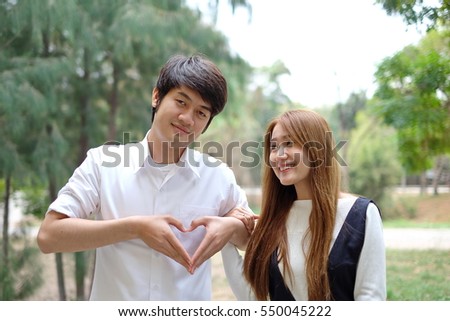Portrait of happy cheerful man and woman in love gesturing heart