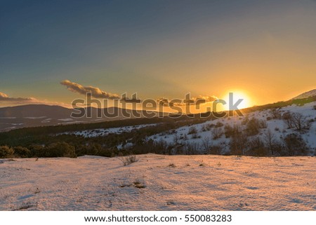 Wonderful orange sunset in snow-covered mountains. Russia, Stary Krym.