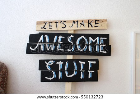 A selfmade sign made of reused pallet wood. Hand written words say "LetÂ´s make Awesome things" written with chalk on a blackboard paint. 
