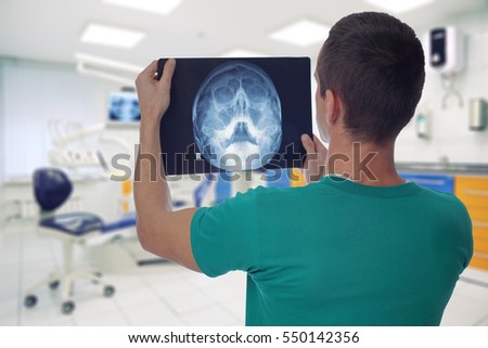 Male doctor dentist watching x-ray of patient