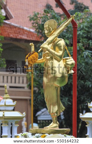 Monk on Pilgrimage Statue Holding Umbrella and Aims Bowl Standing in Front of temple.