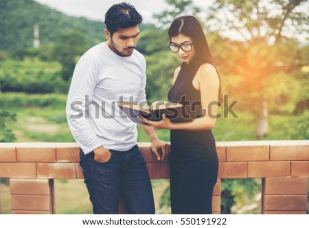 Young hipster couple enjoying a good read together while relaxing outdoors.