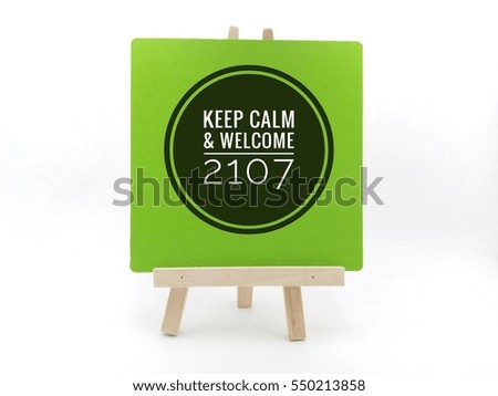 happy new Year 2017 - Conceptual image with word "KEEP CALM & WELCOME 2017" on white green frame and wooden tripod
