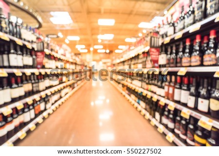 Blurred image of wine shelves with price tags on display at store in Humble, Texas, US. Defocused rows of Wine Liquor bottles on the supermarket shelf. Alcoholic beverage abstract background.