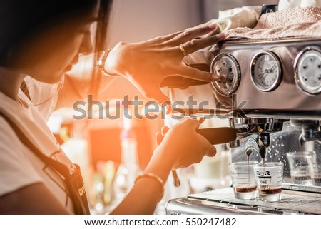 A barista girl is cooking a cup of ice americano coffee. Royalty-Free Stock Photo #550247482