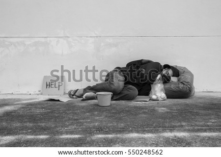 Homeless person sleep on sidewalk of the street Royalty-Free Stock Photo #550248562