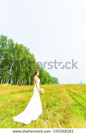 Beautiful bride with wedding bouquet of flowers outdoors in  field