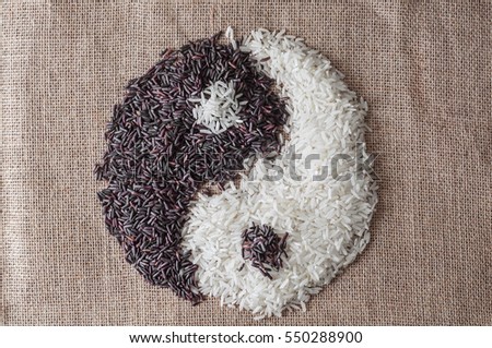 Yin and Yang symbol spelled by two kind of raw rice on burlap background