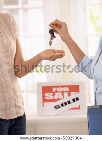Estate agent handing over keys of new house to young owner.