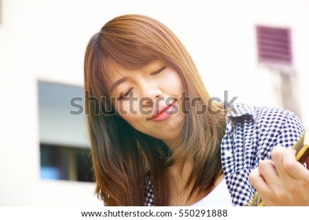 Woman in casual dress in playing guitar with happily face.