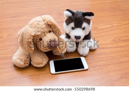 Siberian husky and golden retriever fur doll lay down on wooden floor looking at smart phone screen for relaxing.