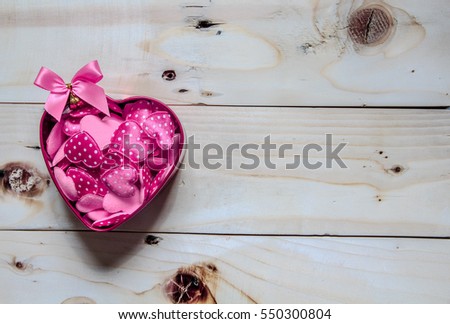 Heart-shaped box with a small heart. On the wooden floor.