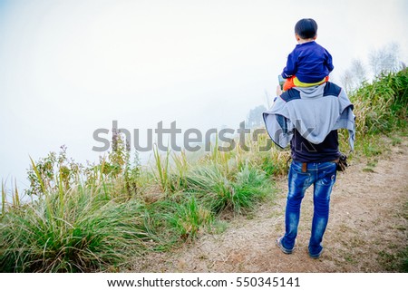 Son sits on his father's neck.The family enjoyed a holiday Holiday over blurred beautiful nature.Concept People and family.