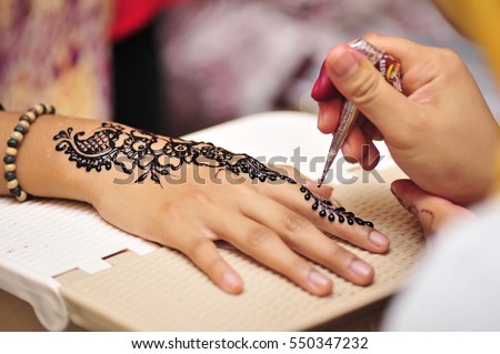 Artist applying henna tattoo on bride hands. Mehndi is traditional Indian decorative art. Close-up