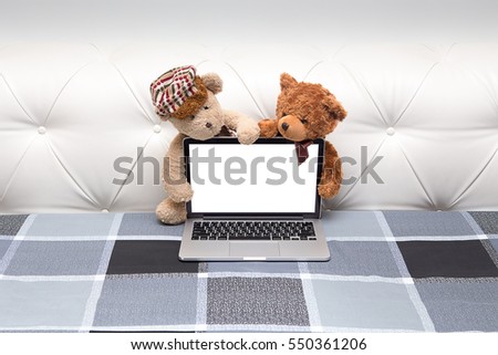 Couple Teddy Bear sitting behind the screen and watching movie on laptop computer sitting on vintage bed.