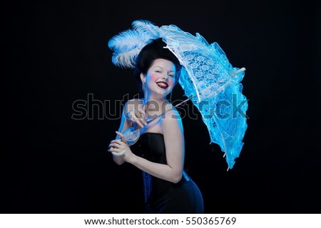 emotional actress brunette woman in an ancient medieval attire and lush hair with white feathers with a white lace umbrella in hand on a black background in the studio