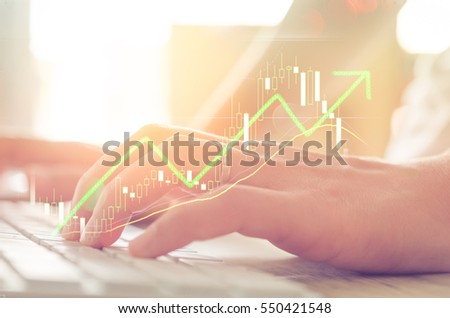 Business economic and technology working concept. Woman hand using mouse pc double exposure graph money stock trading up trend green arrow bokeh background. Vintage tone filter effect color style.