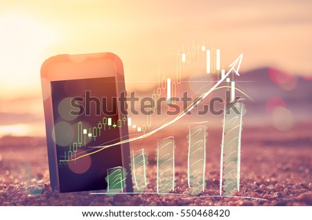Business economic technology and freedom trader working concept. Smart phone on sand sunset beach double exposure graph money stock trading up trend arrow bar bokeh background. Vintage filter color 