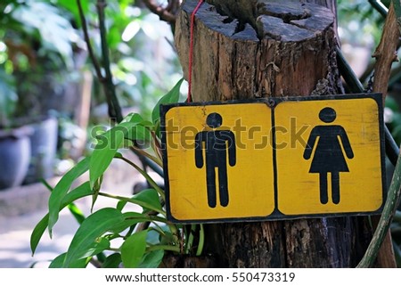 Yellow wooden square shape of public restroom toilet sign for man and woman closeup fresh outdoor park nature blur background