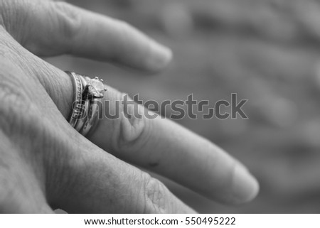 Single Wedding Ring on Woman's Hand on Sandy Beach Shore in Black and White
