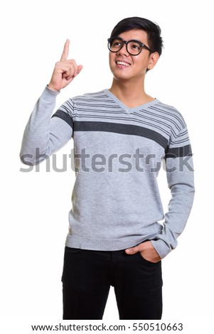 Studio shot of happy Asian man smiling and pointing finger up while thinking isolated against white background