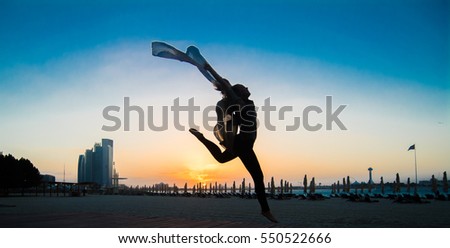 Life is beautiful, a lady dances in joy as sun sets in Abu Dhabi Beach. City of Abu Dhabi is well known as luxury holidays so as beach destination. 