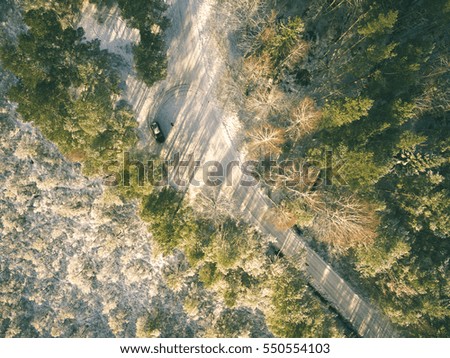 aerial view of snowy forest in sunny winter day with country road. drone photography - vintage effect