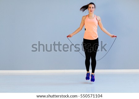 Beautiful sports girl doing exercises with jumping rope. Royalty-Free Stock Photo #550571104