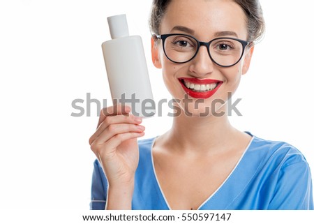 Portrait of a young smiling cosmetologist holding a bottle with cosmetics. Studio shot isolated on white background