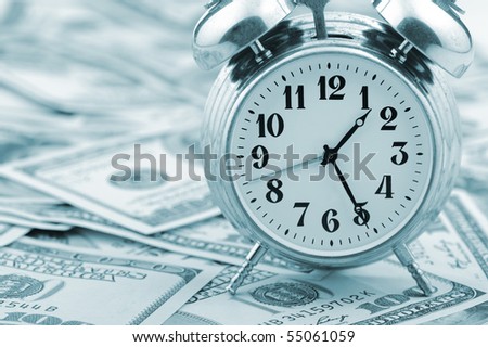 Time - money. Business concept. Analog hours on a heap of paper dollars. Blue tone