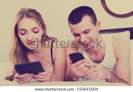 Young adults together reading news from e-readers 