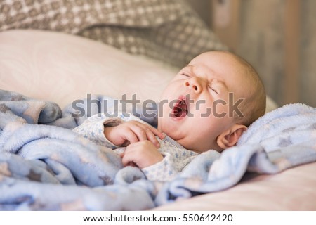 Cute baby yawning before sleep Royalty-Free Stock Photo #550642420