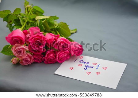 Pink roses and i love you text on a white note