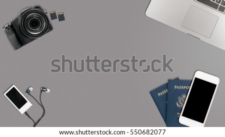 Clean and tidy grey desk with equipment ready for travel including camera, laptop, phone, music player and passports Royalty-Free Stock Photo #550682077