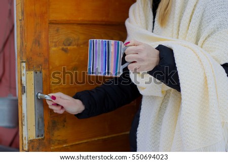 woman holding a hot cup of tea in her hands outdoors in winter, numbed female hands with polished nails